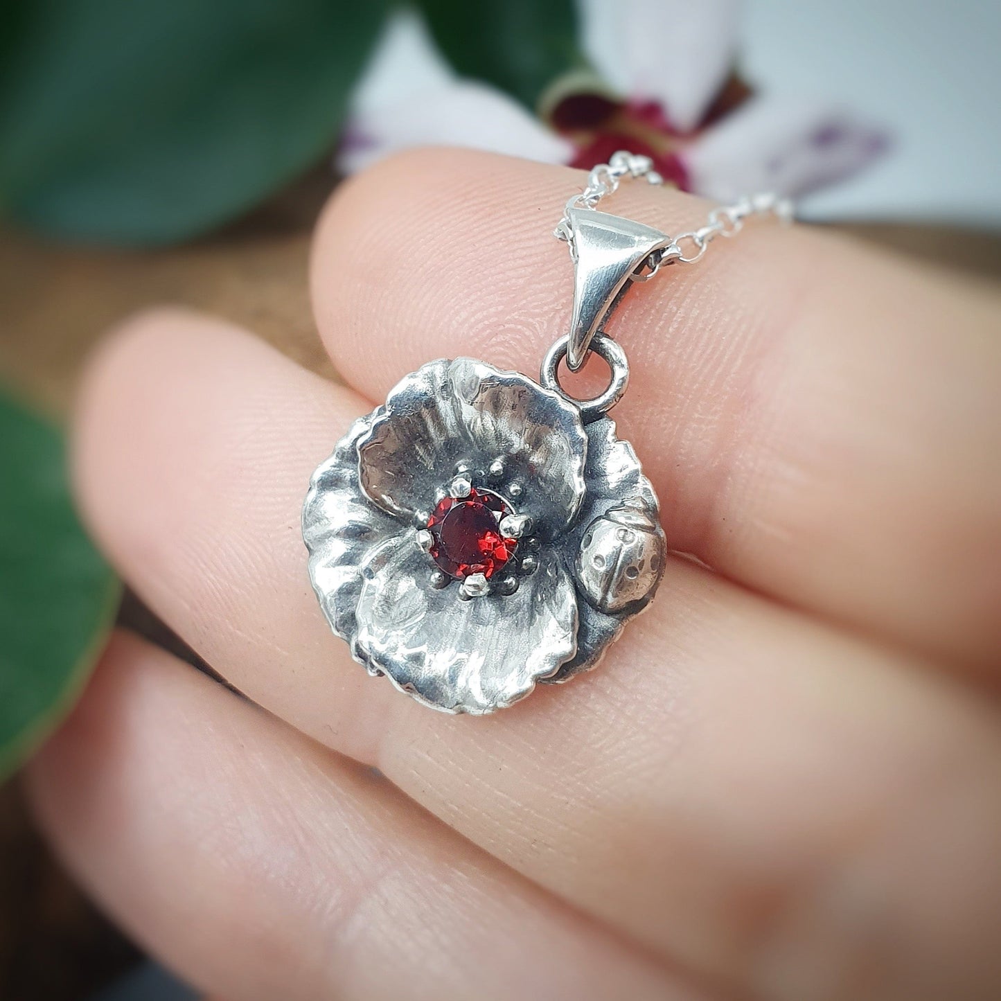 Ciondolo in argento 925 con papavero e coccinella, incastonato al centro un granato taglio brillante.