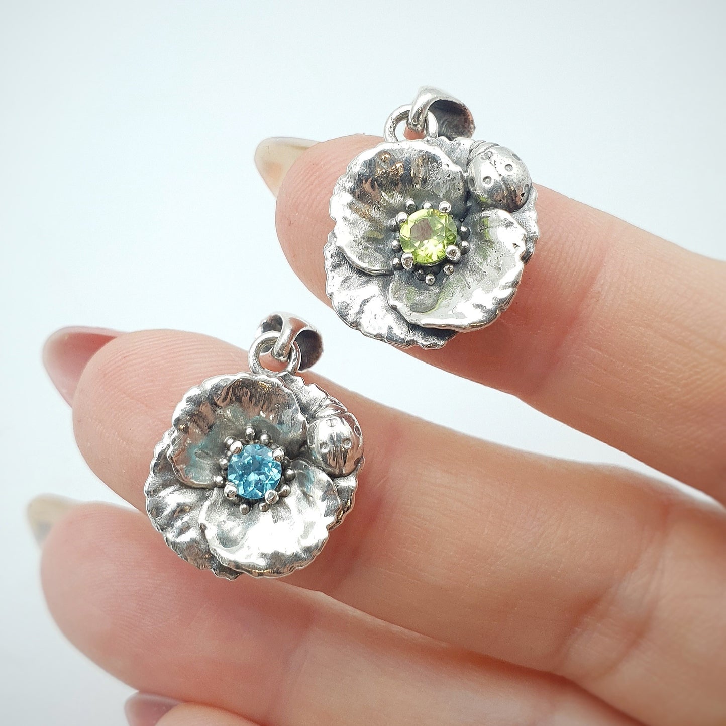 Ciondoli in argento 925 con papavero e coccinella, incastonati al centro un peridoto e un'apatite taglio brillante.