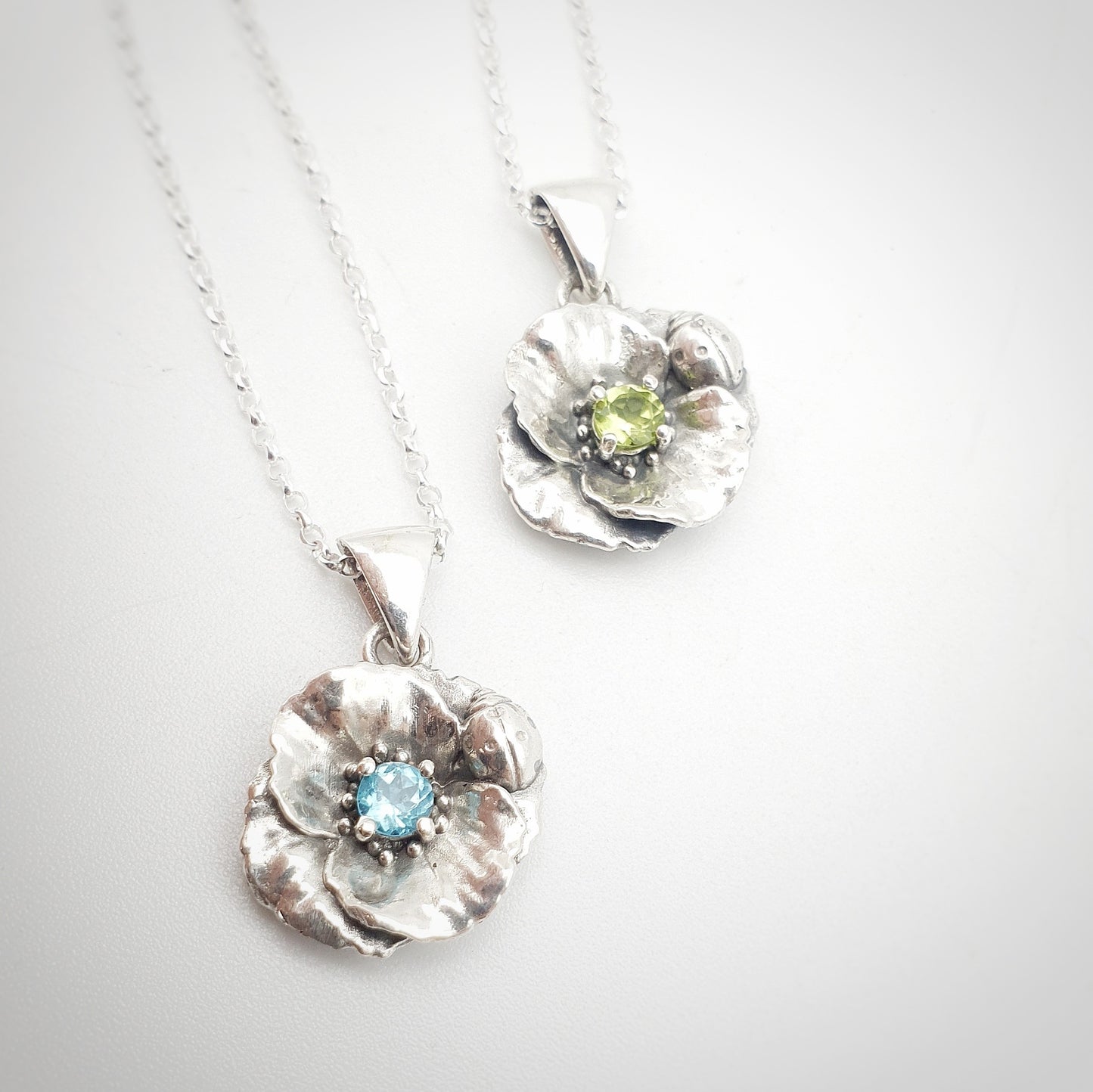 Ciondoli in argento 925 con papavero e coccinella, incastonati al centro un peridoto e un'apatite taglio brillante.