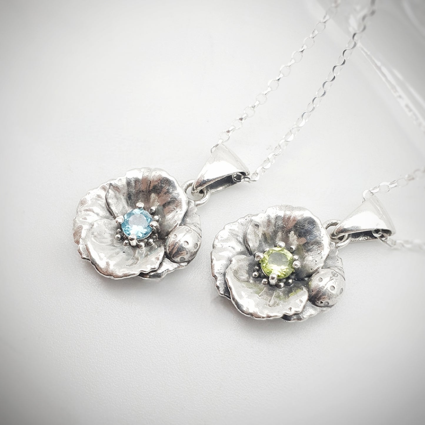 Ciondoli in argento 925 con papavero e coccinella, incastonati al centro un peridoto e un'apatite taglio brillante.