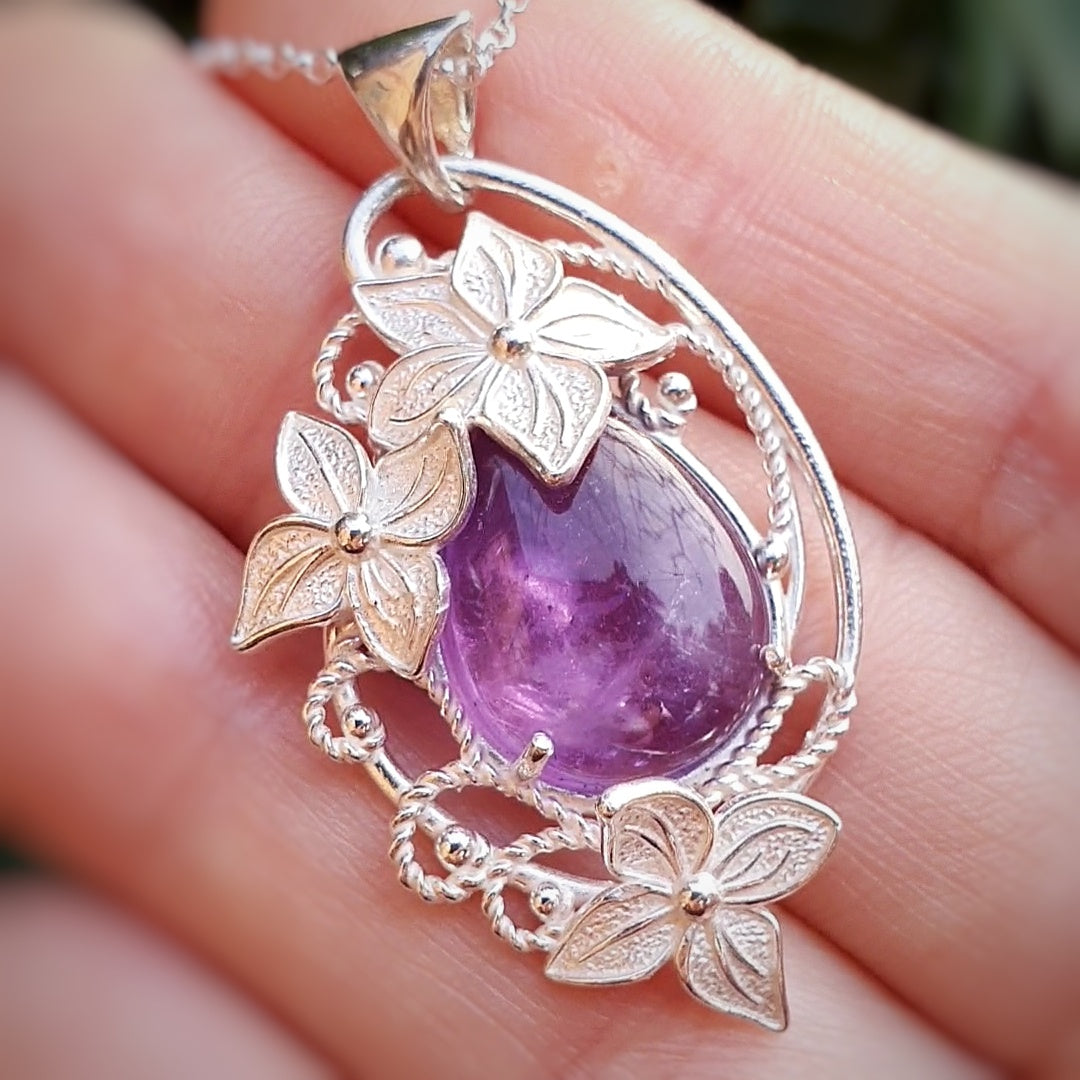 Ciondolo in argento 925 con fantasia di fili lisci e intrecciati, decorato con fiori stilizzati.
