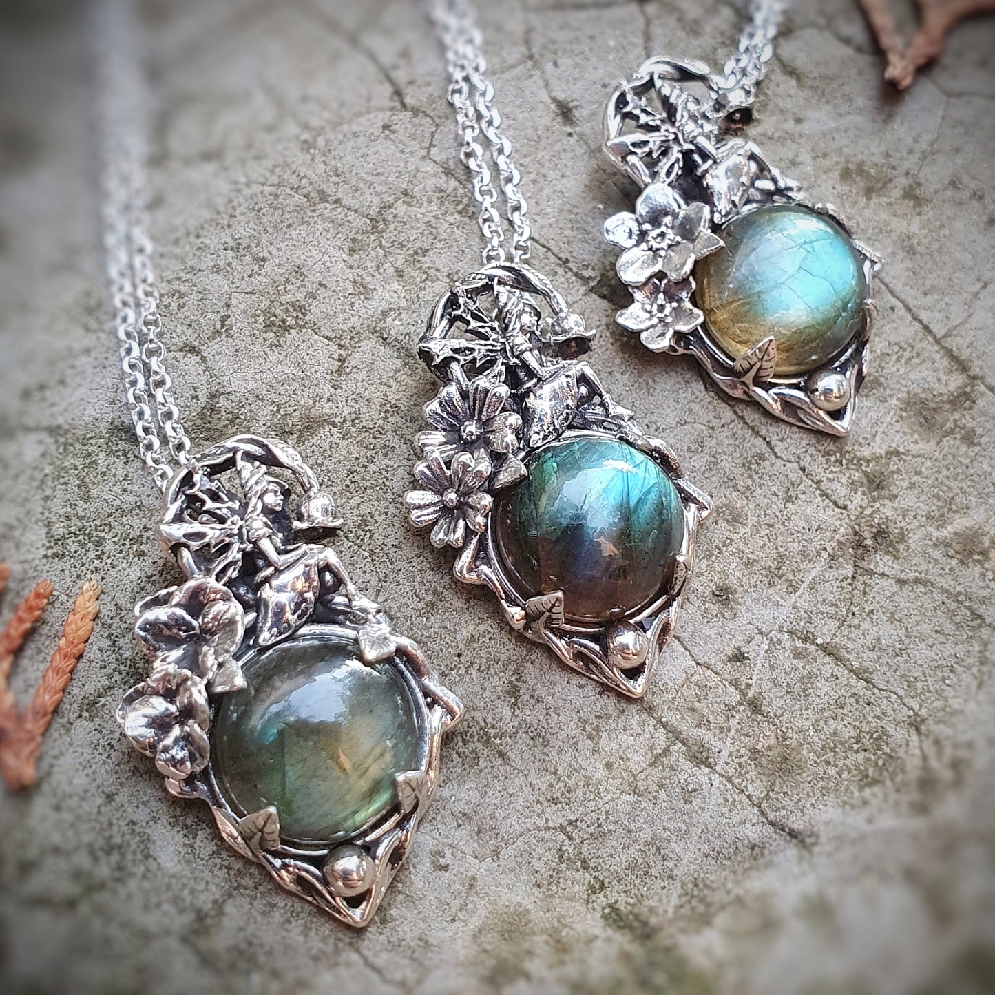 Ciondoli in argento 925 con cabochon di labradorite multicolor, una fata e decorazioni floreali di viola, myosothis e primula.