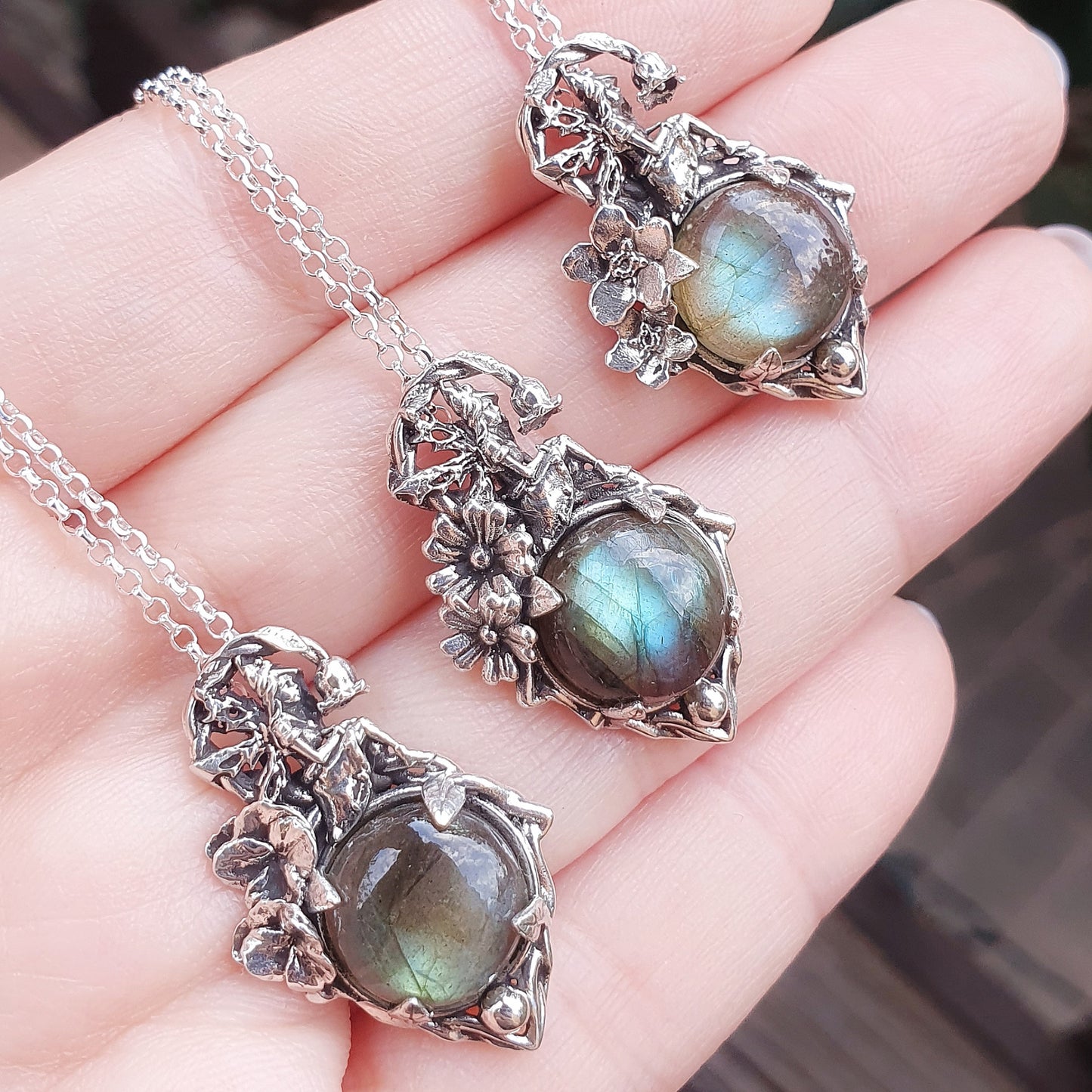 Ciondoli in argento 925 con cabochon di labradorite multicolor, una fata e decorazioni floreali di viola, myosothis e primula.