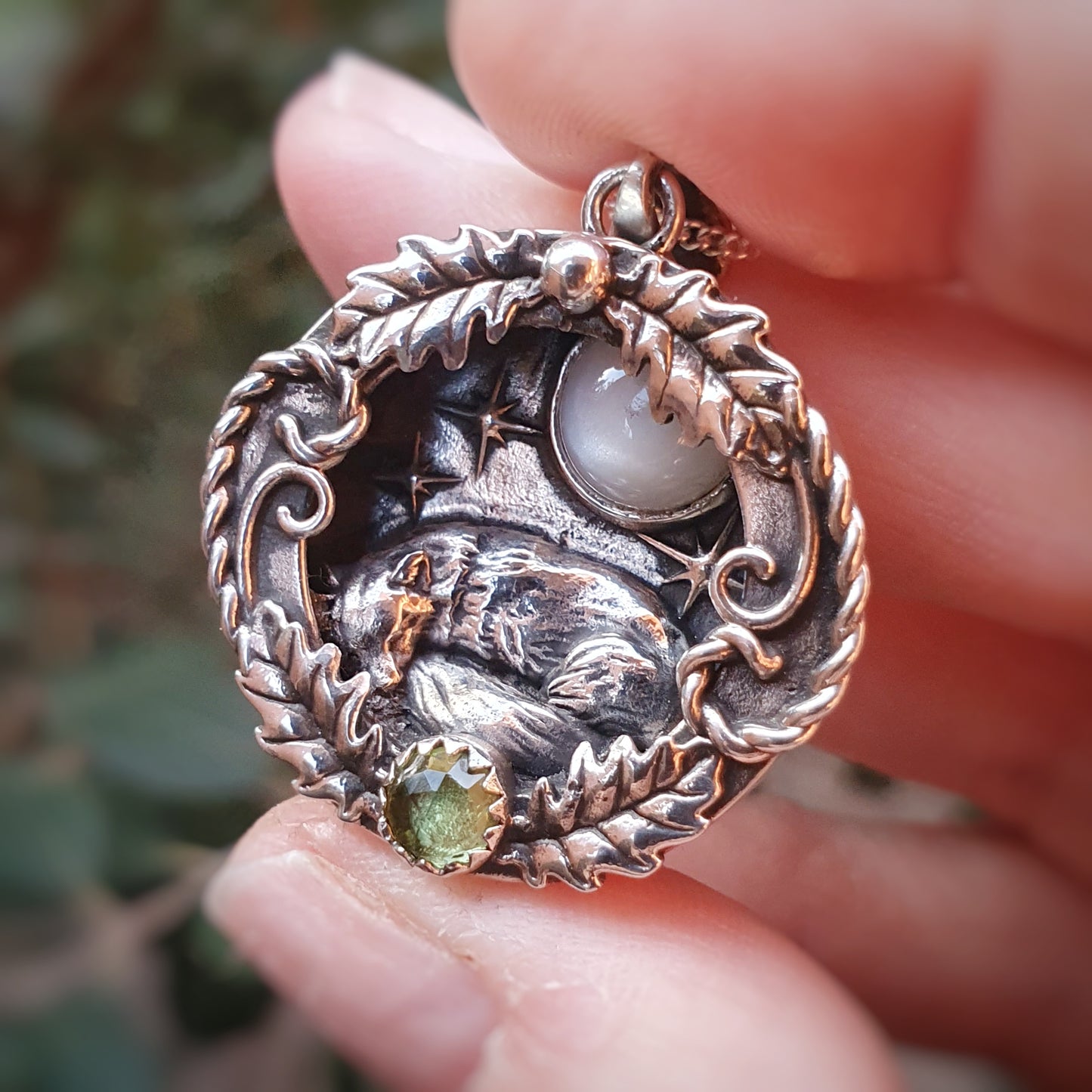 Ciondolo incassato in argento 925 con labradorite bianca e peridoto, raffigura una volpe che dorme sotto un cielo stellato, avvolta in decorazioni di foglie di quercia e riccioli.