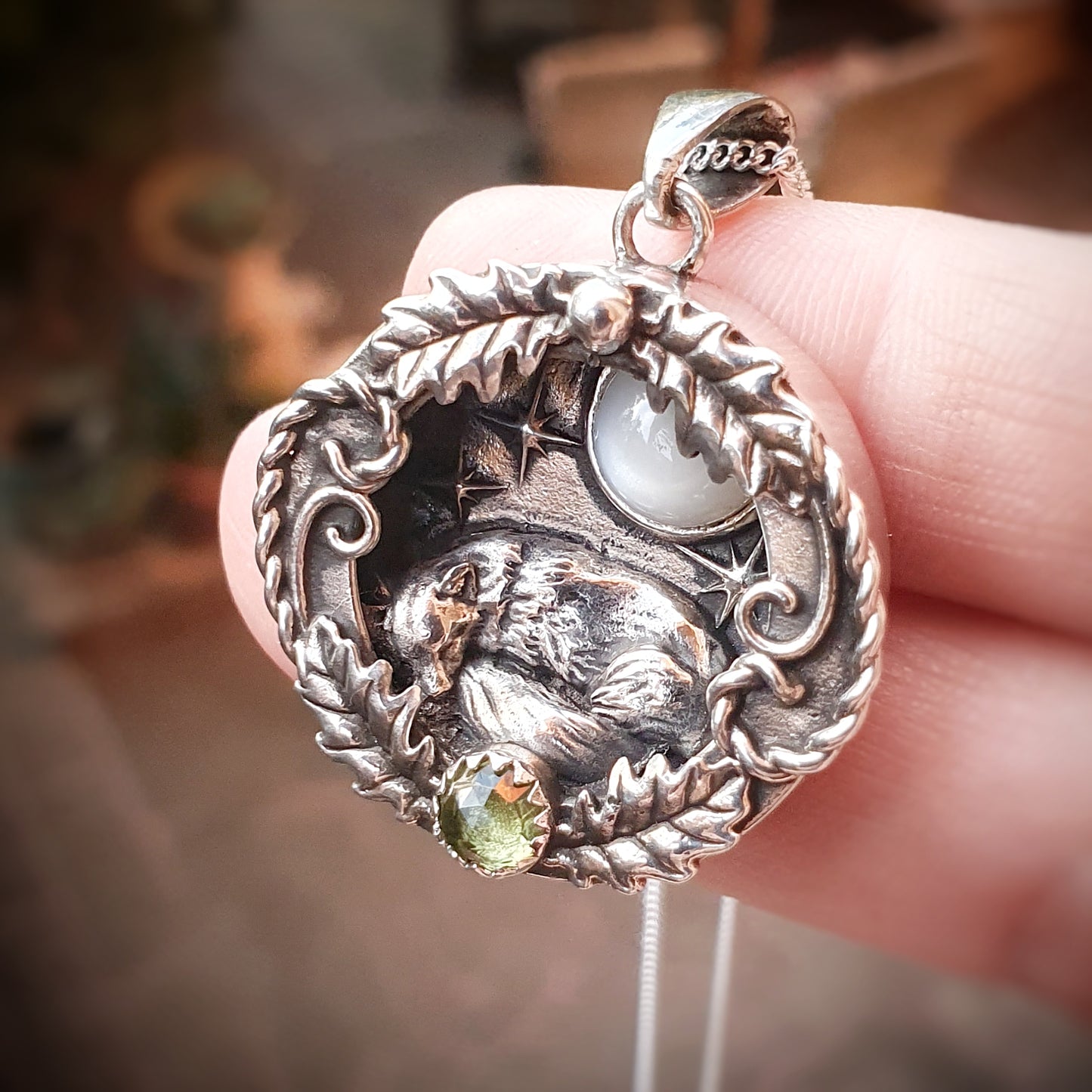 Ciondolo incassato in argento 925 con labradorite bianca e peridoto, raffigura una volpe che dorme sotto un cielo stellato, avvolta in decorazioni di foglie di quercia e riccioli.
