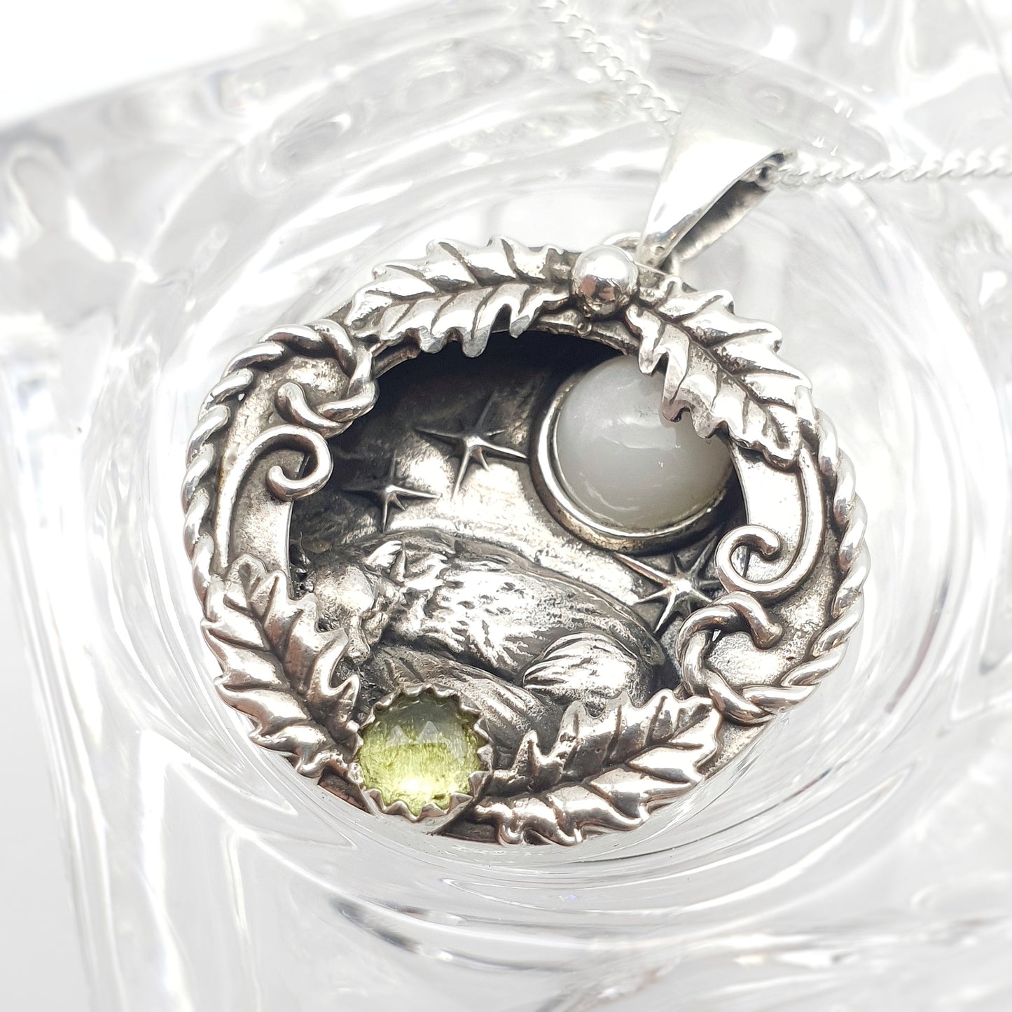 Ciondolo incassato in argento 925 con labradorite bianca e peridoto, raffigura una volpe che dorme sotto un cielo stellato, avvolta in decorazioni di foglie di quercia e riccioli.