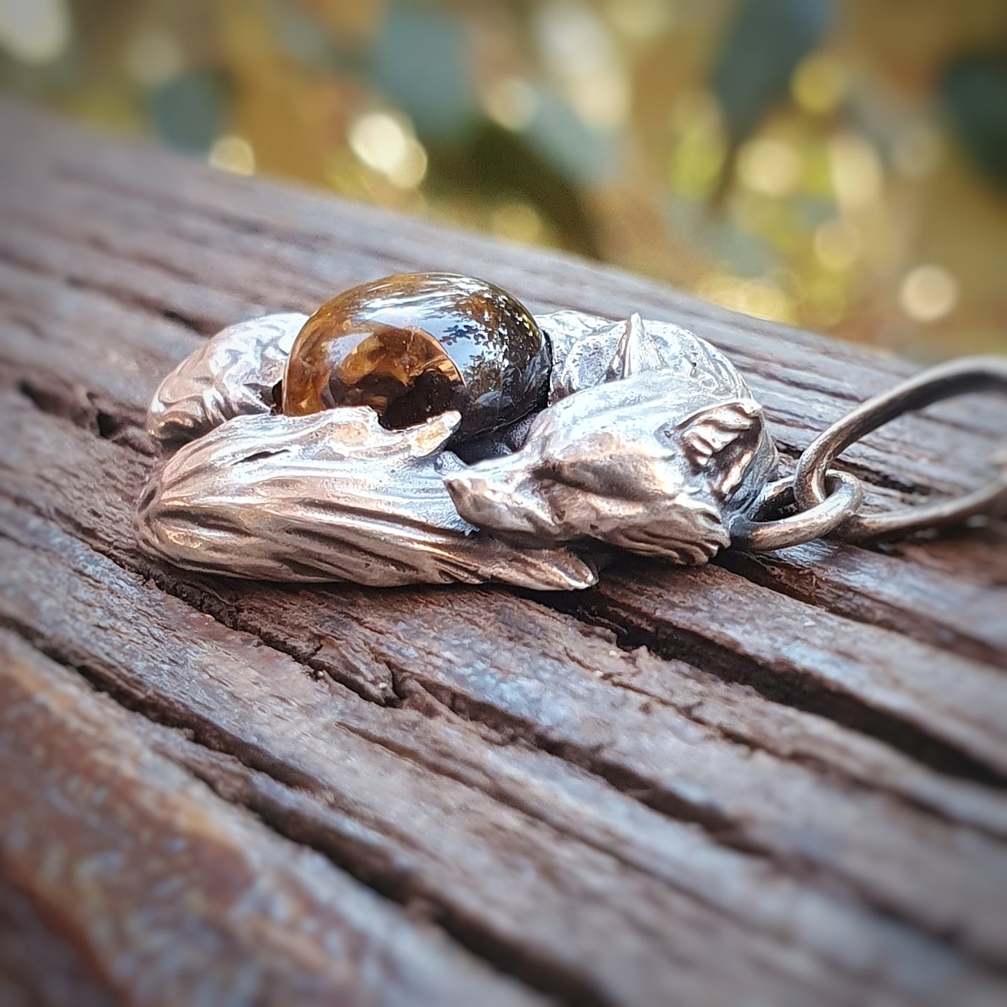 Una micro-scultura in argento 925 raffigurante una volpe acciambellata attorno ad un cabochon di occhio di tigre.