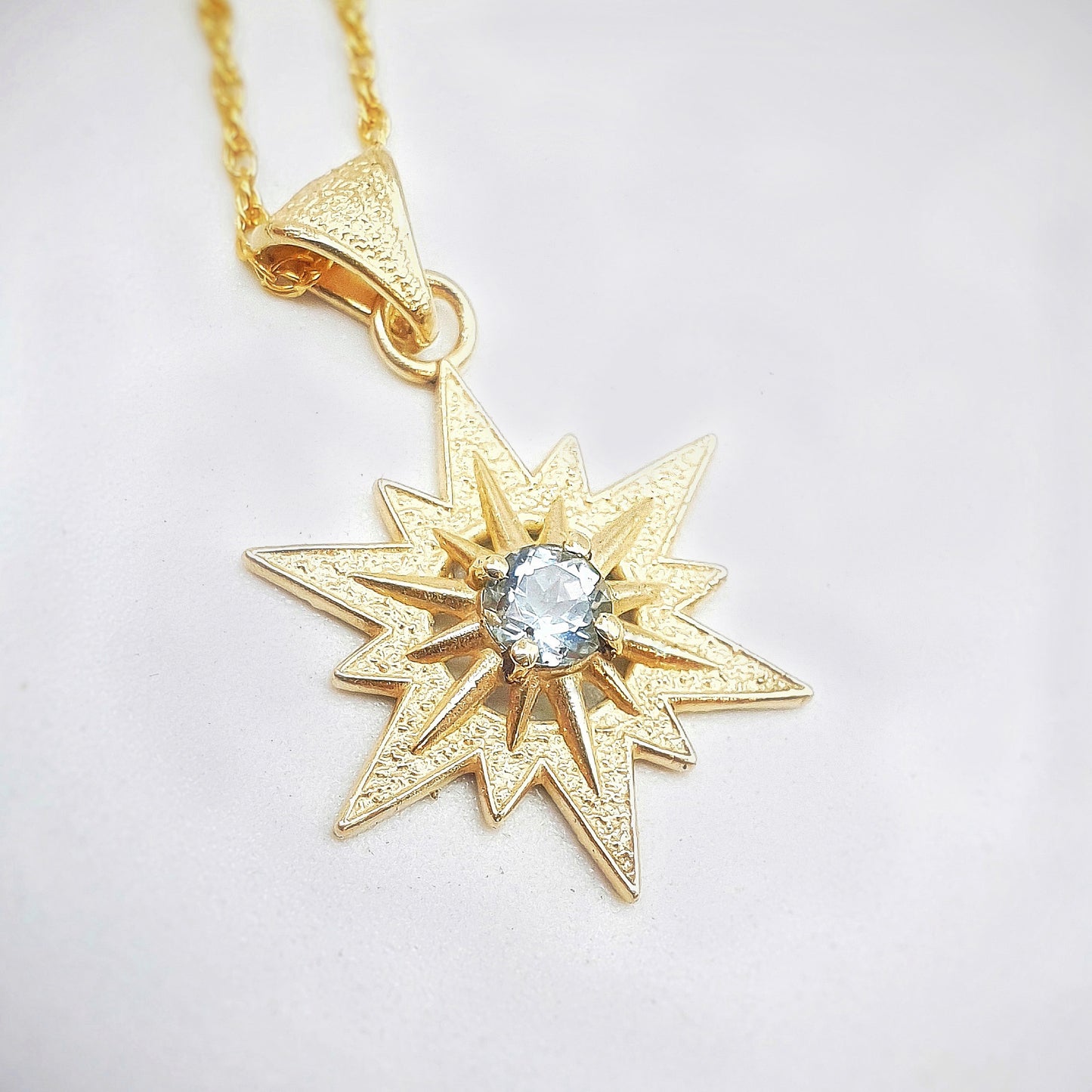 Ciondolo in oro giallo 9 kt raffigurante la stella di Betlemme, con acquamarina taglio brillante.