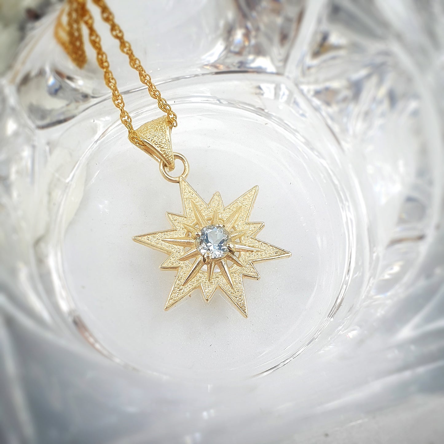 Ciondolo in oro giallo 9 kt raffigurante la stella di Betlemme, con acquamarina taglio brillante.