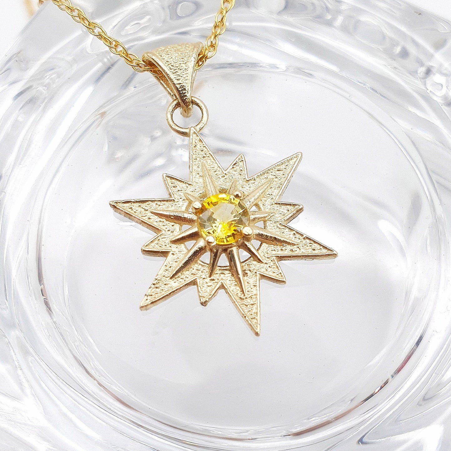 Ciondolo in oro giallo 9 kt raffigurante la stella di Betlemme, con zaffiro giallo taglio brillante.