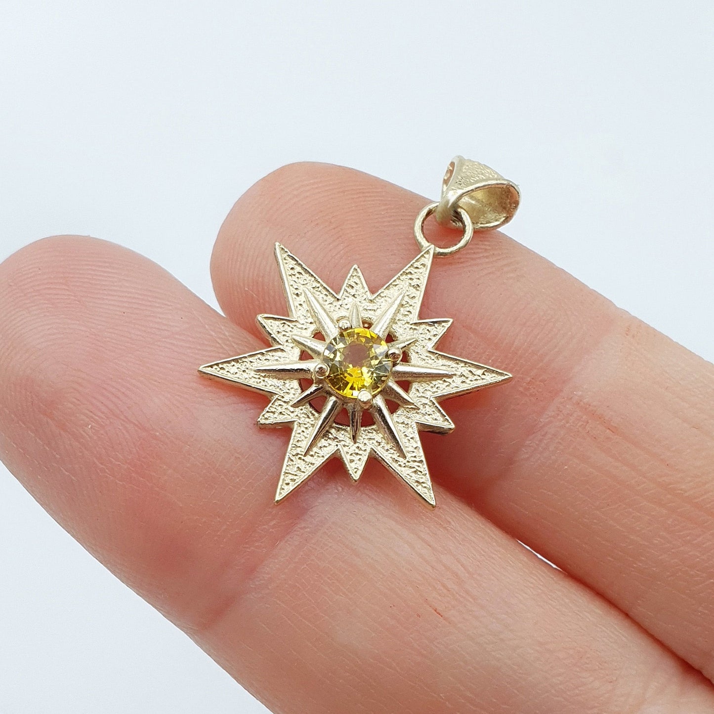 Ciondolo in oro giallo 9 kt raffigurante la stella di Betlemme, con zaffiro giallo taglio brillante.