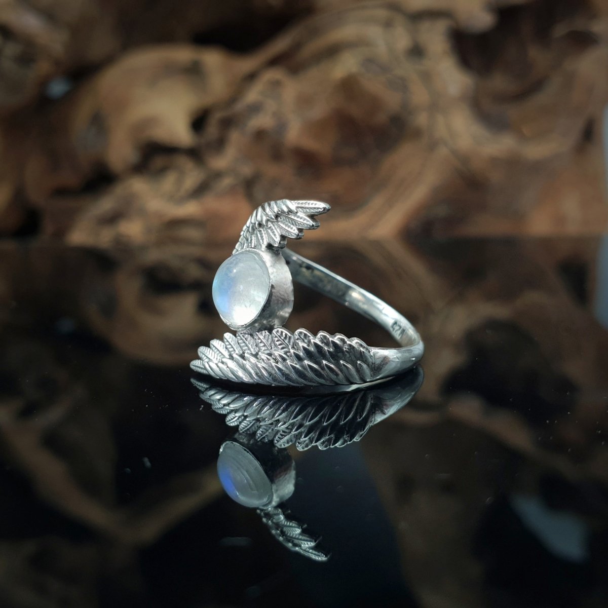 Anello in argento 925, due ali abbracciano un cabochon rotondo di labradorite bianca.
